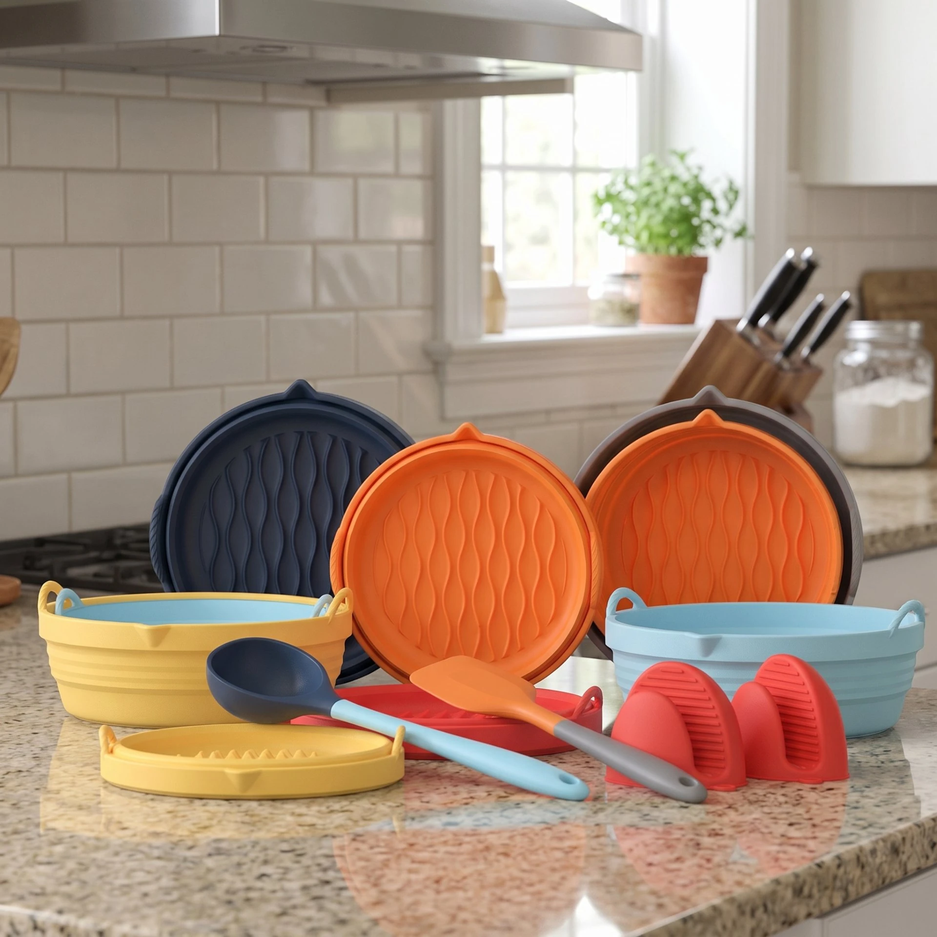 Colorful collapsible silicone bowls, lids and trivets arranged on a kitchen countertop
